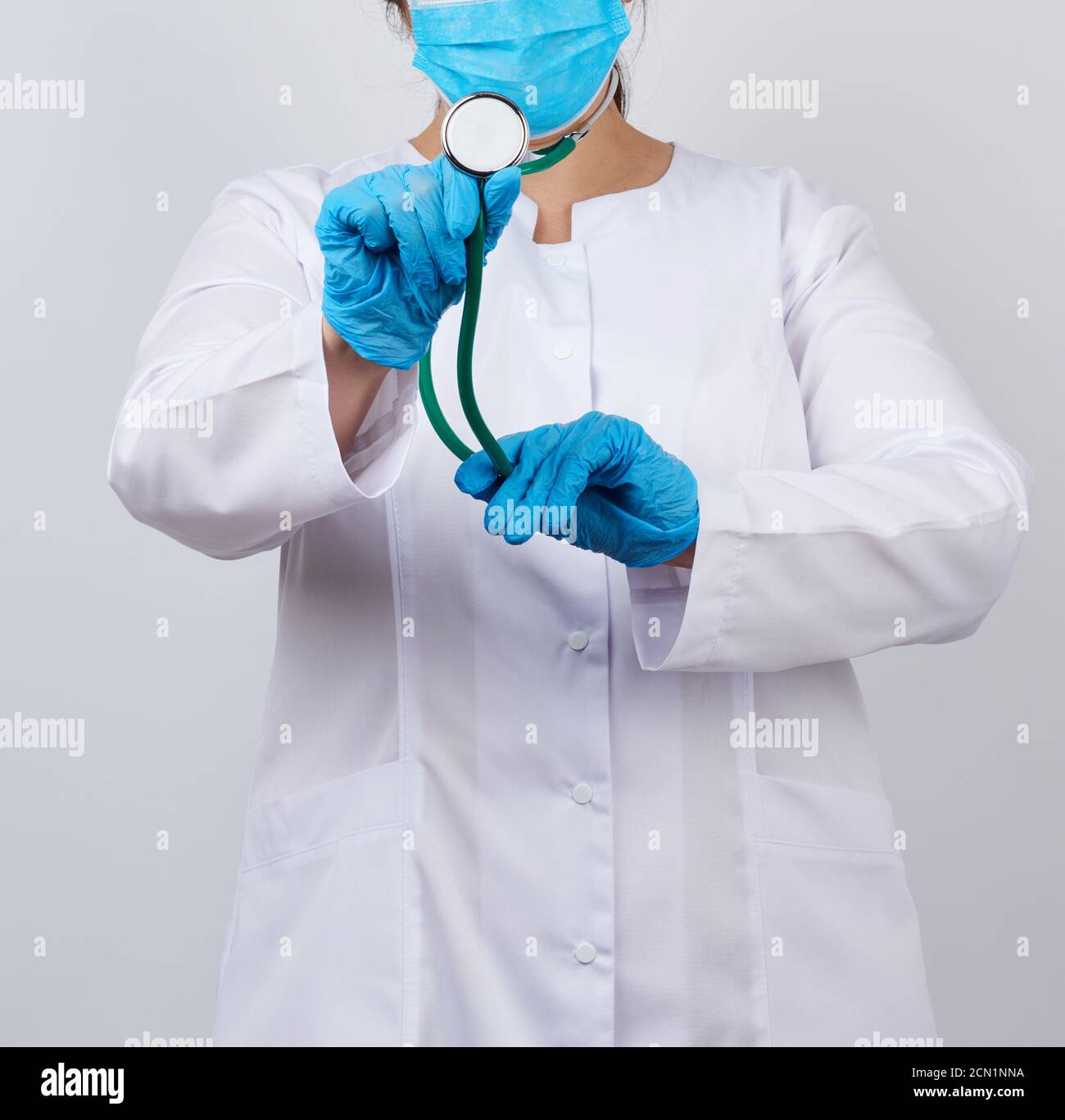 medic woman in a white coat and mask, wearing blue medical latex gloves ...