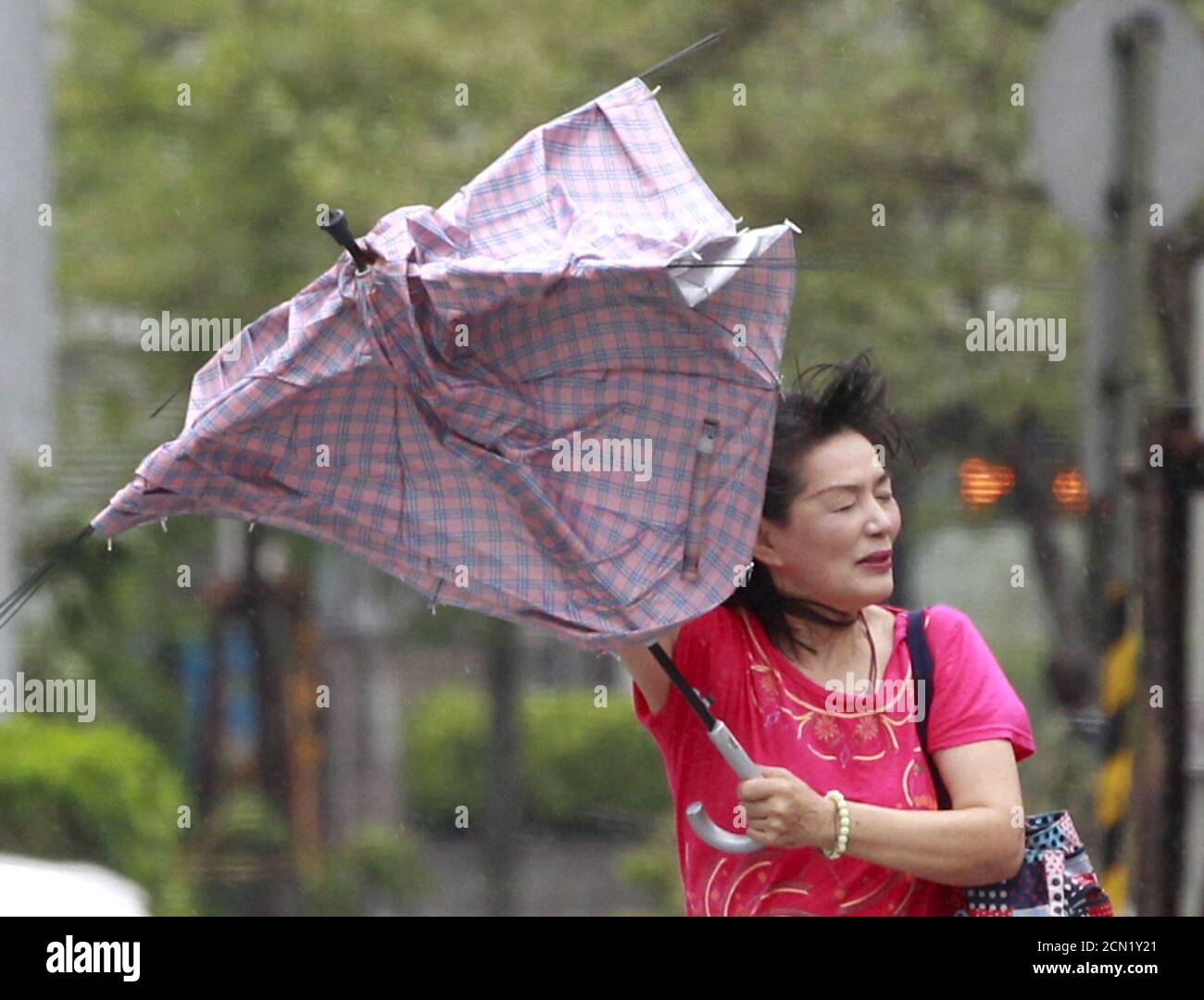 A woman holds her umbrella while walking against strong wind in Taipei as Typhoon Soudelor hits Taiwan August 8, 2015. A powerful typhoon battered Taiwan on Saturday with strong wind and torrential rain, cutting power to nearly 3 million households and killing four people. REUTERS/Pichi Chuang Stock Photo