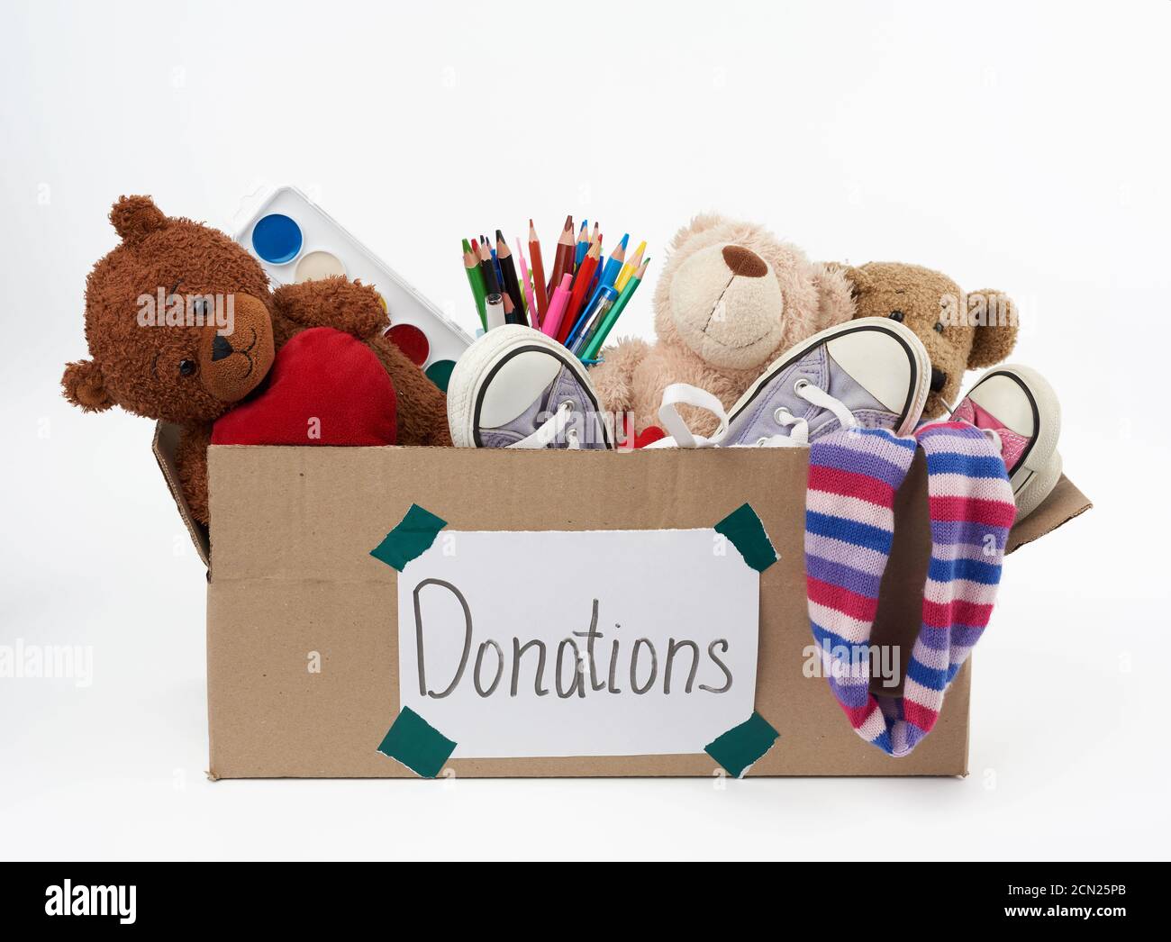 brown cardboard box filled with soft toys, school supplies on white