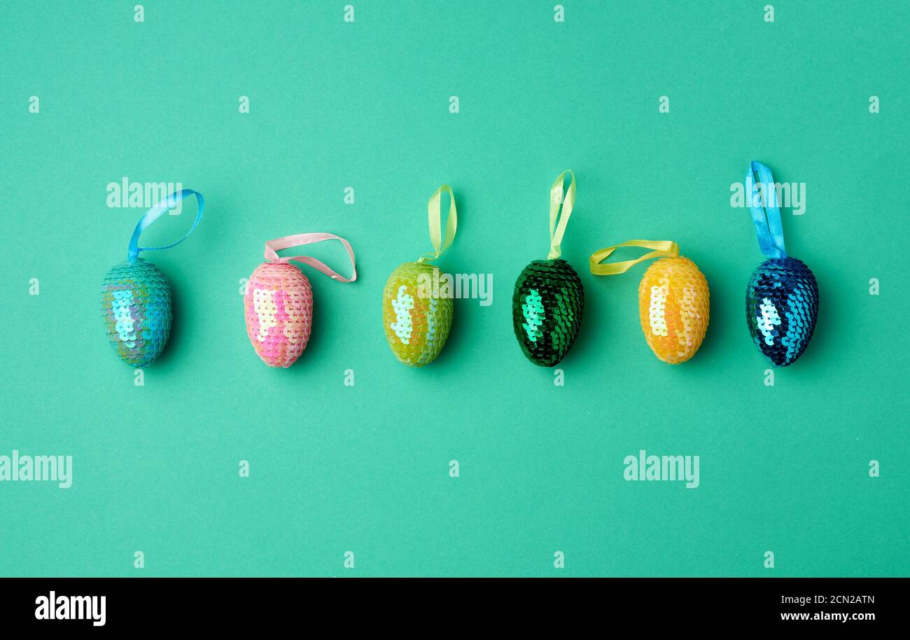 multicolored decorative Easter eggs decorated with sequins on a green background Stock Photo