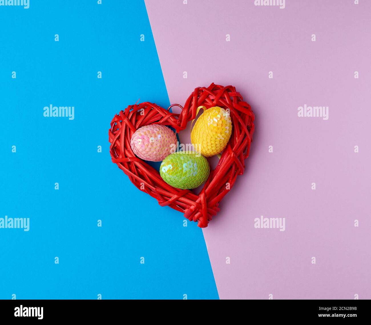 multicolored decorative Easter eggs decorated with sequins on a blue purple background Stock Photo