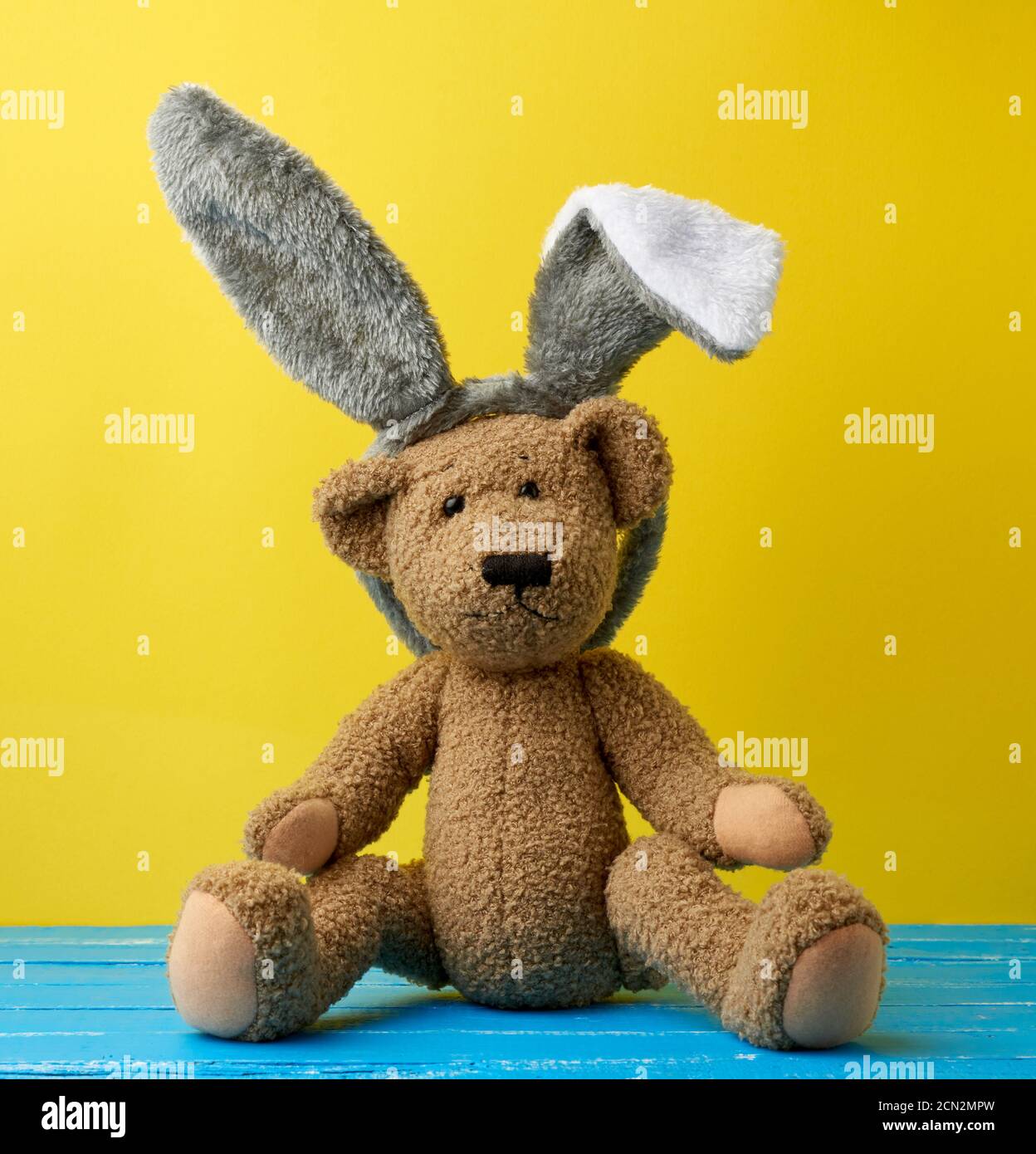 cute brown teddy bear wearing a rabbit mask with long ears on his head