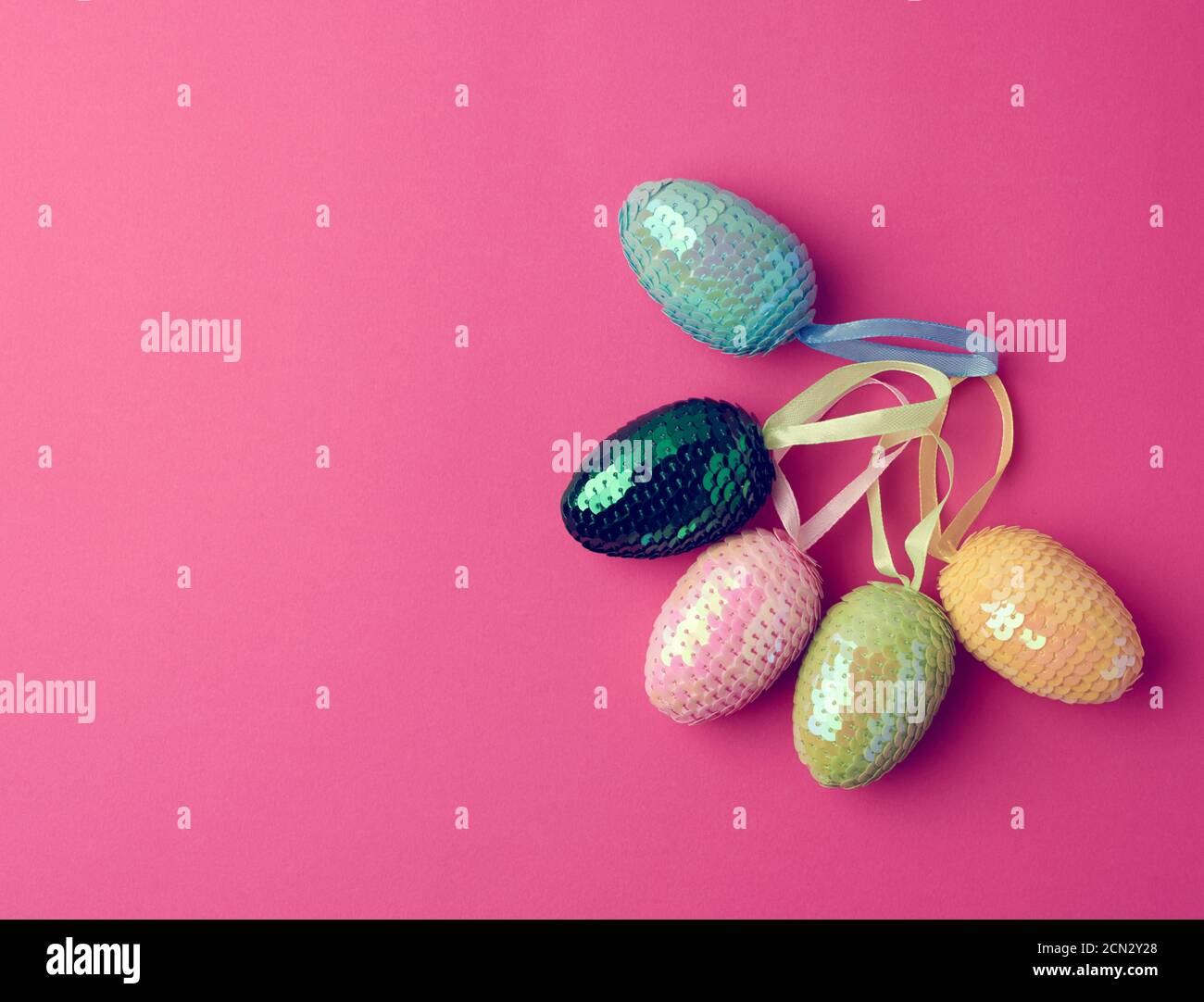 multicolored decorative Easter eggs decorated with sequins on a pink background Stock Photo