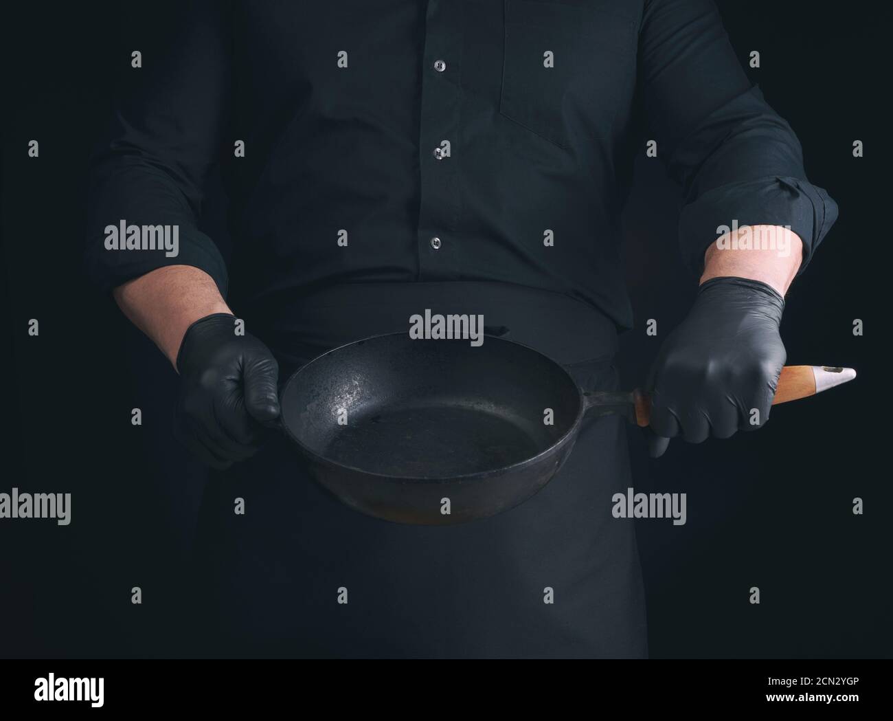 male cook in black uniform and latex gloves holds an empty round