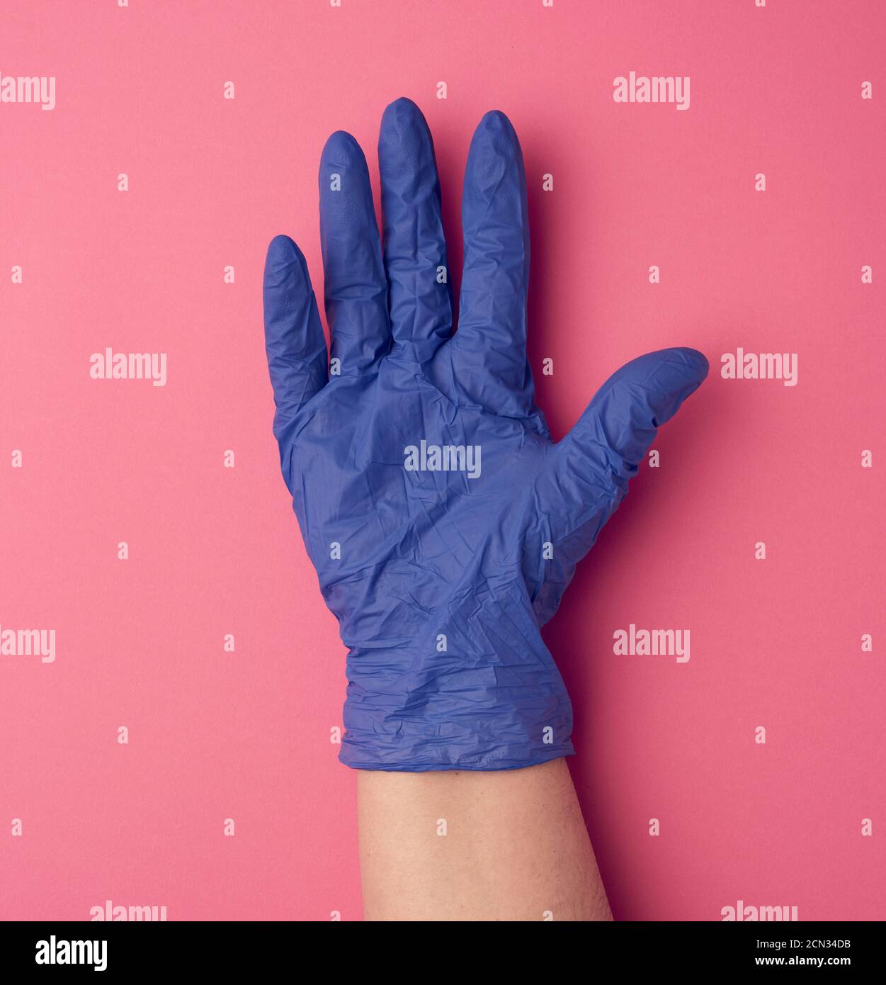 blue medical glove is worn on the arm, part of the body on a pink