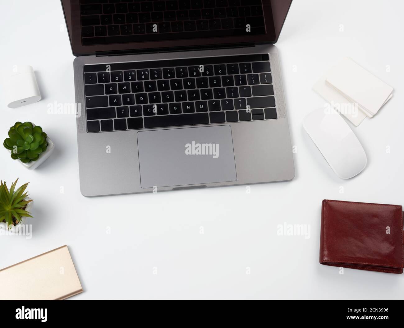 open gray laptop stands on a white table, next to a wireless mouse, freelancer workplace, businessma Stock Photo