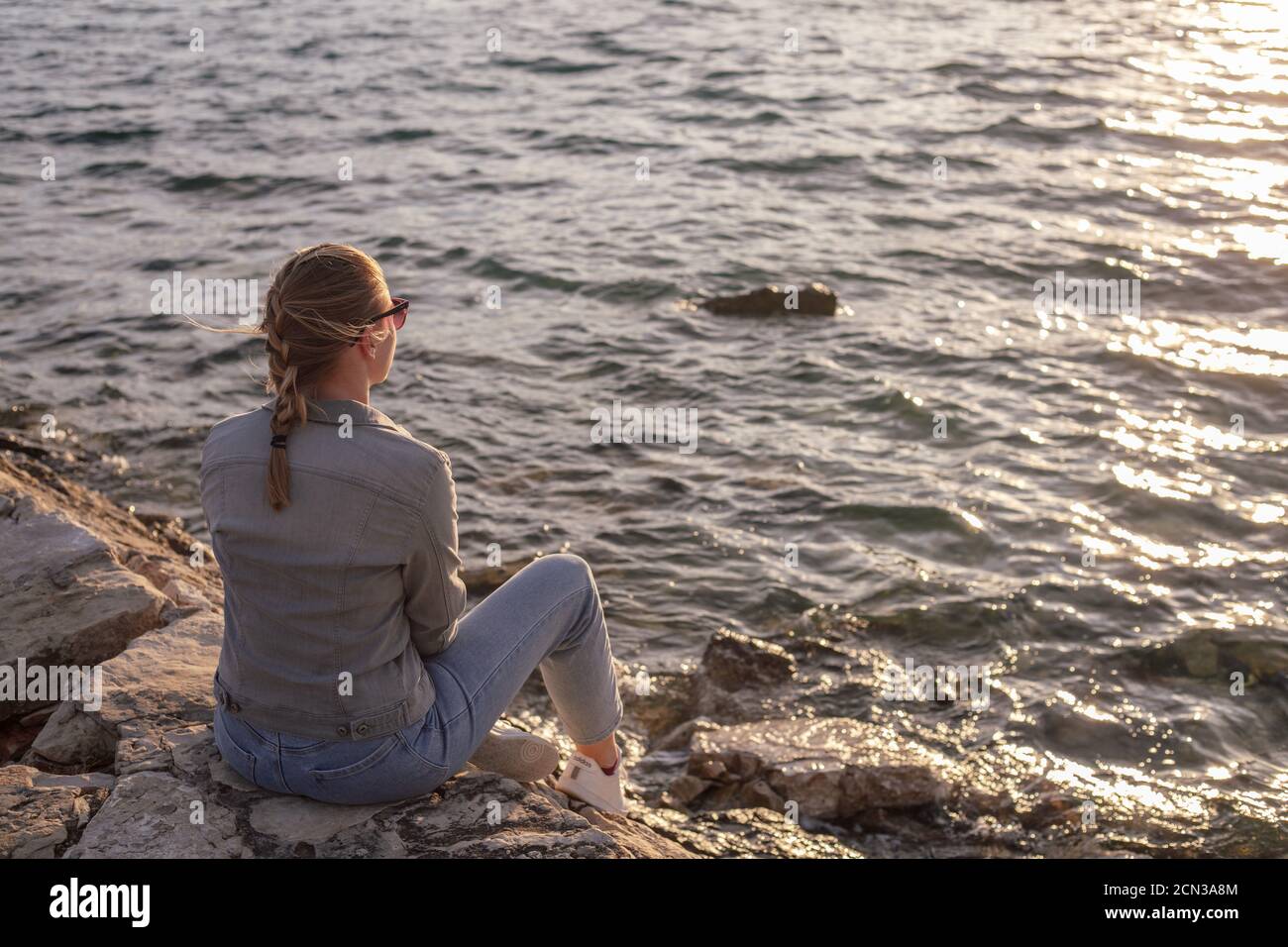 Back view of woman sitting by the sea Stock Photo - Alamy