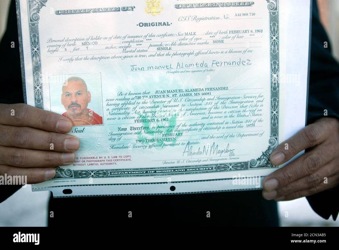 Juan Alameda holding up his certificate of derivative citizenship. Stock Photo