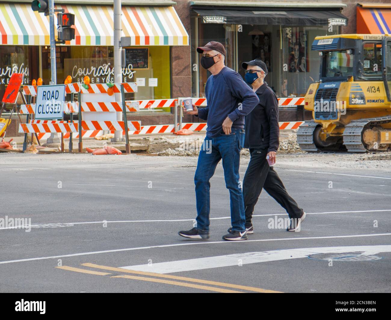 Two men wearing face masks crossing street during COVID-19 pandemic. Oak Park, Illinois. Stock Photo
