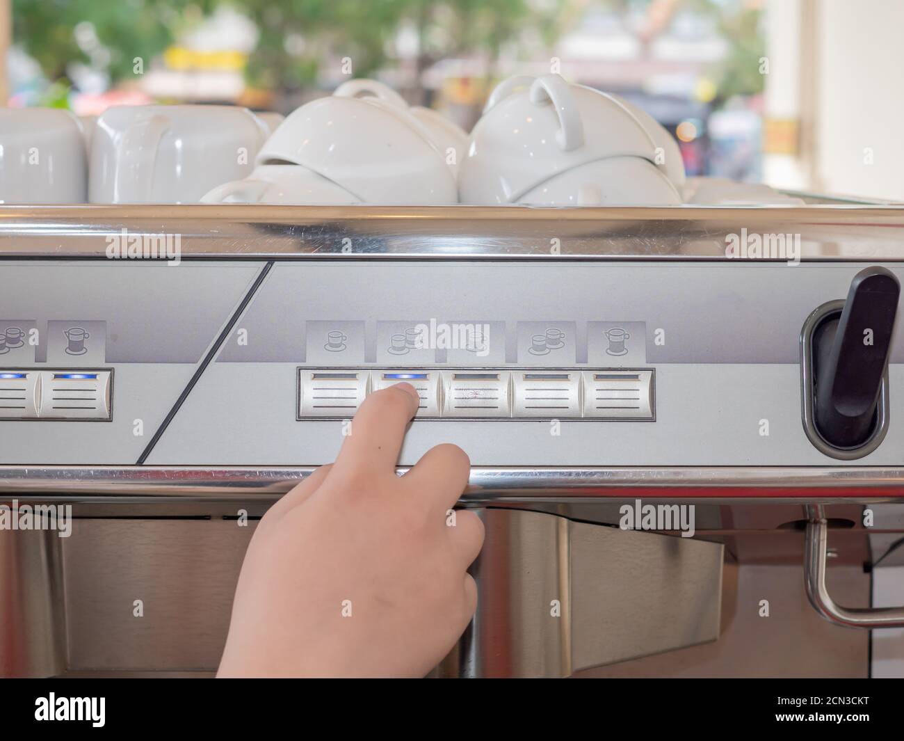 The barista's hand is pressing the button on the coffee machine with a ...
