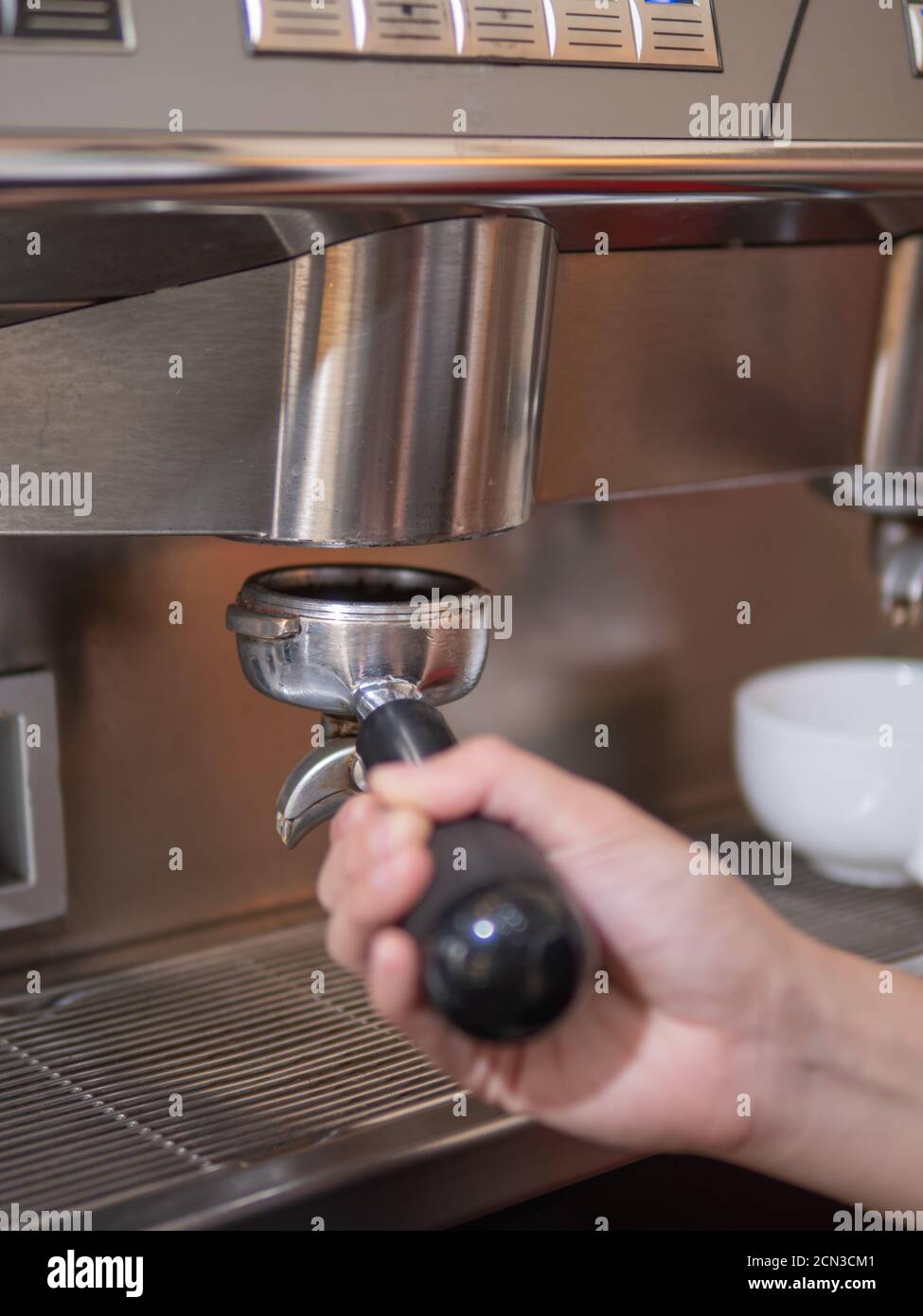 Focus on portafilter putting to group head of the espresso machine by barista's hand Stock Photo