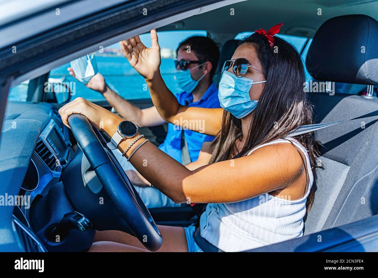 Couple with facemask arguing while she is driving a car in a dangerous Stock Photo