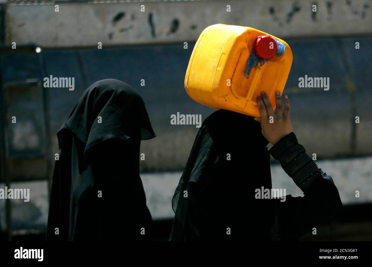 A woman carries a container filled with water from a public tap in Sanaa in this picture taken February 3, 2010. More water is consumed than produced from most of Yemen's 21 aquifers, especially in the highlands, home to big cities like Sanaa, with a fast-growing population of two million, and Taiz. Yemen's water crisis is worsened by excessive irrigation by farmers growing qat, a mild narcotic leaf that dominates life in Yemen, where most men spend half the day chewing it, even at work. Picture taken February 3, 2010. To match feature YEMEN-WATER/   REUTERS/Khaled Abdullah (YEMEN - Tags: SOCI Stock Photo