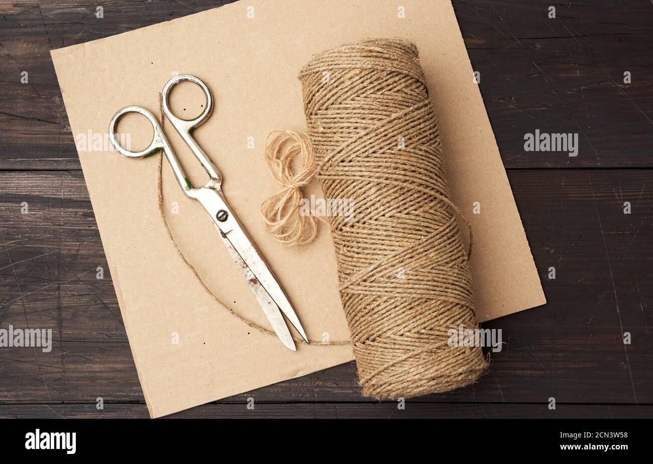 wn thread twisted into a spool and vintage metal scissors on a wooden background from boards Stock Photo