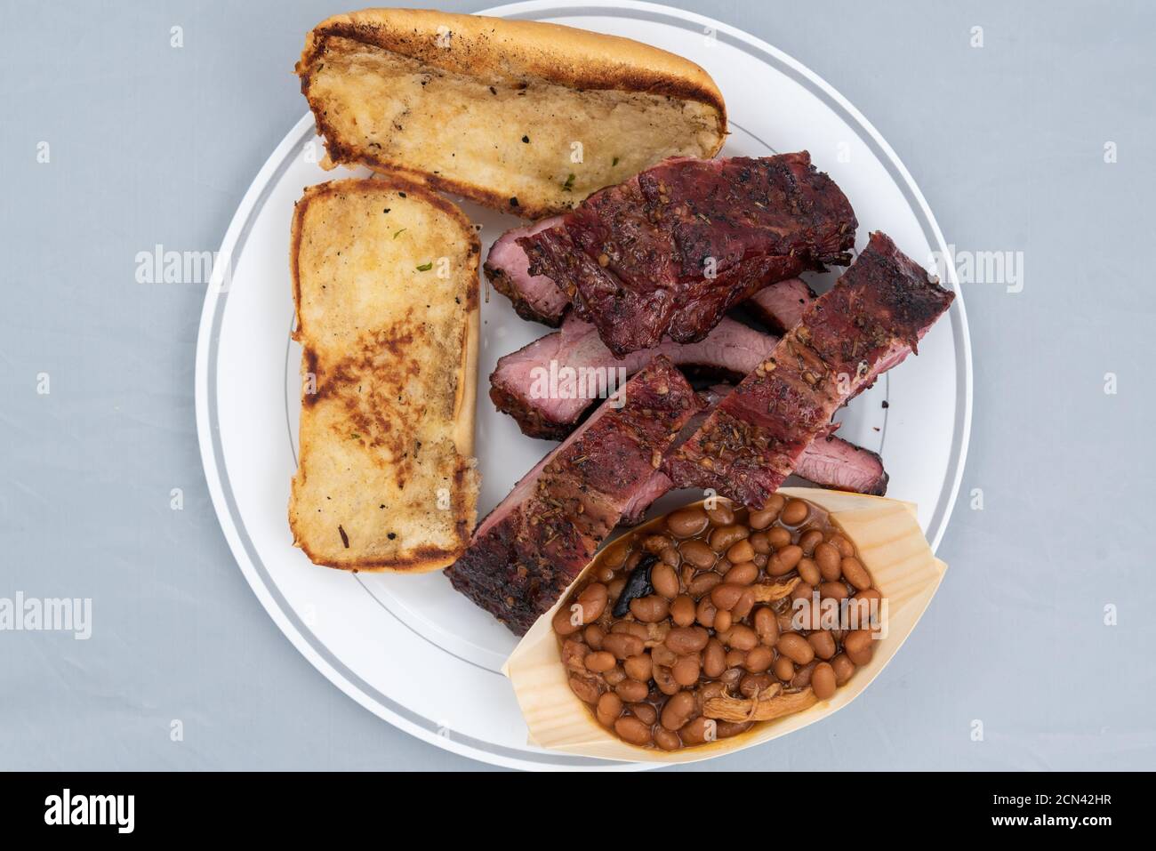 Overhead view of meal of half slab of ribs, baked beans, and butter