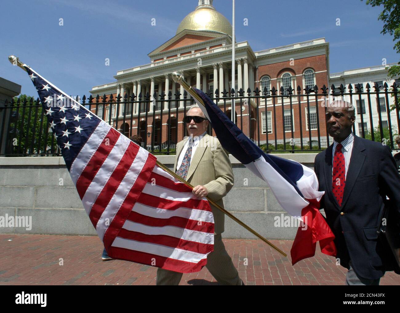 U.S. citizens John Hermanson (L) and Enoch Woodhouse (R) of the Massachusetts Lafayette society carry United States and French flags side by side at the Massachusetts Statehouse (rear) in Boston, May 20, 2003. Woodhouse and Hermanson were on their way to ceremonies commemorating the 169th anniversary of the death the Marquis de Lafayette, a French General and politician who became a hero in the American revolutionary war. French and local officials joined together at the event in reasserting the common democratic values of the two countries despite recent diplomatic and military policy differe Stock Photo