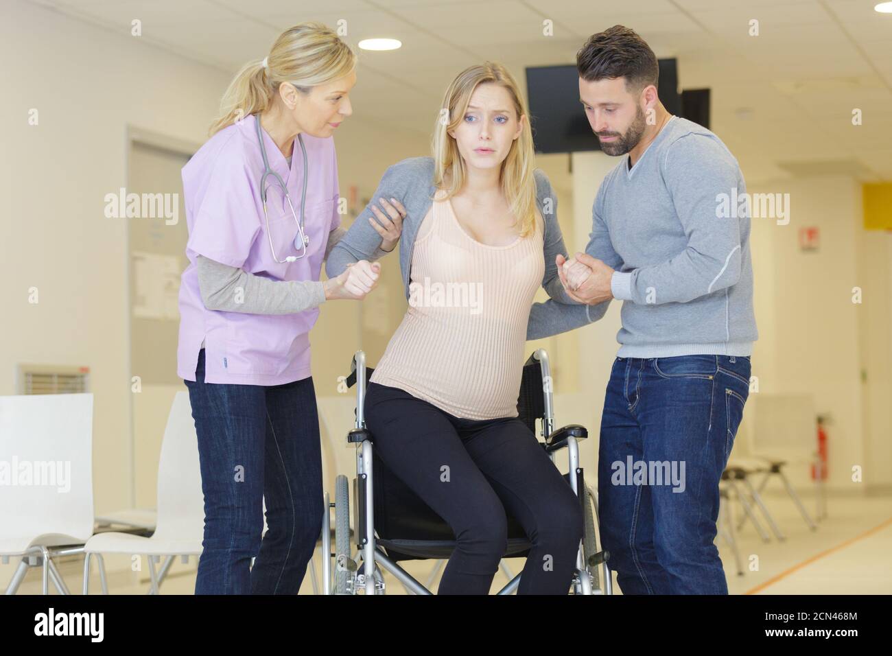pregnant woman being helping into a wheelchair Stock Photo Alamy