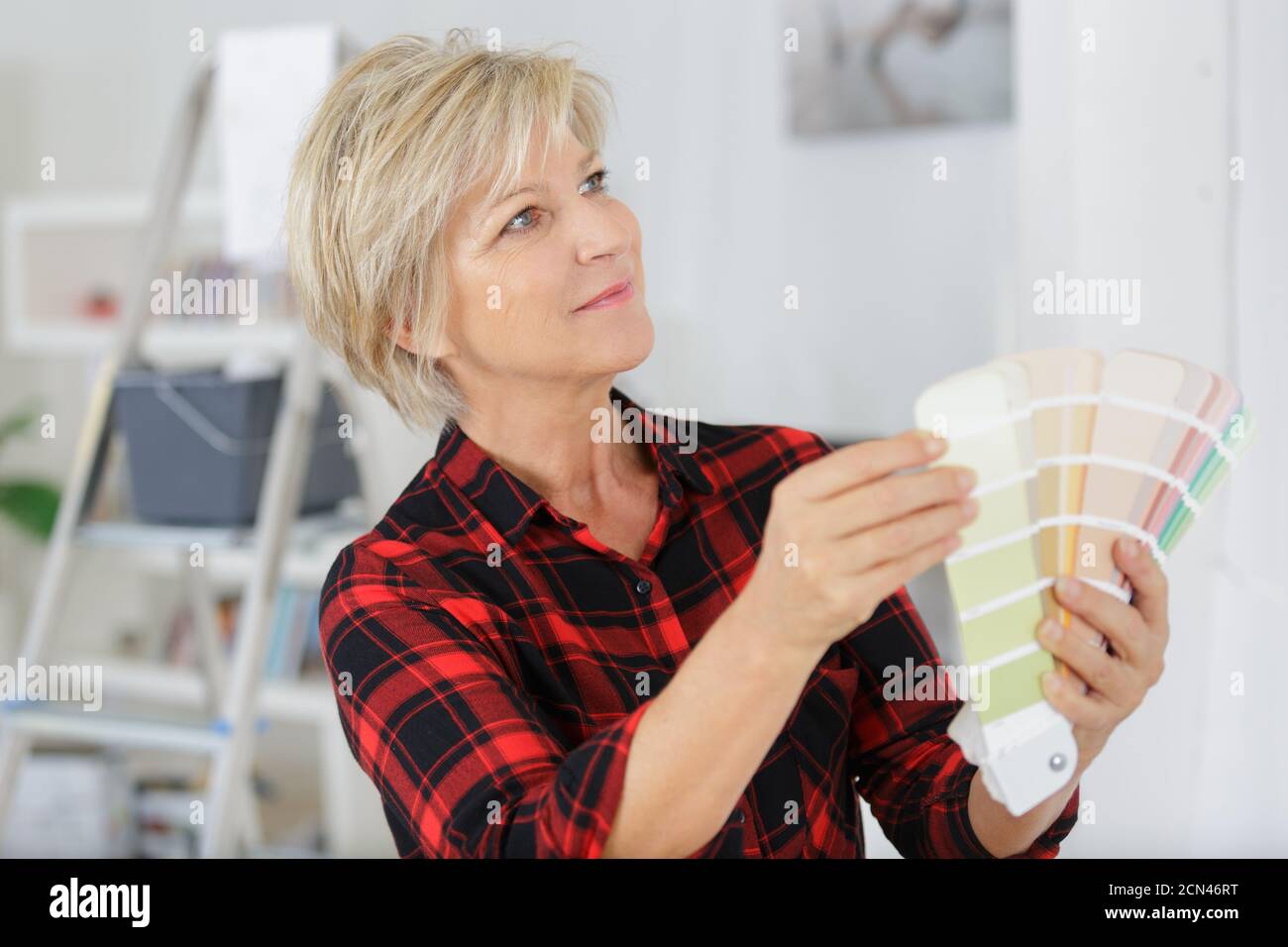 senior woman deciding on a new paint color Stock Photo