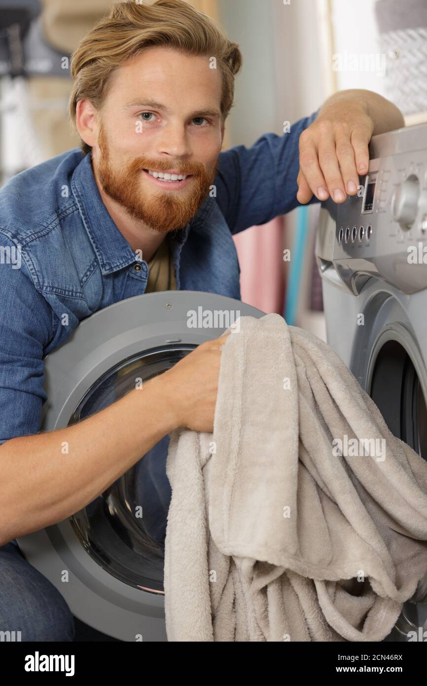male loading dirty clothes in washing machine Stock Photo