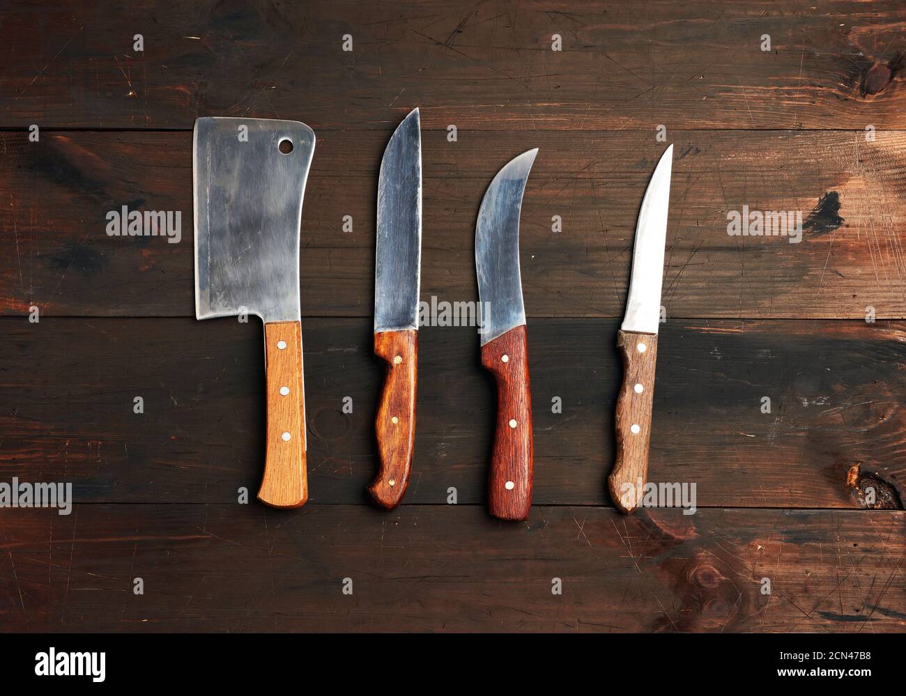 set of different kitchen knives with wooden handles on a brown