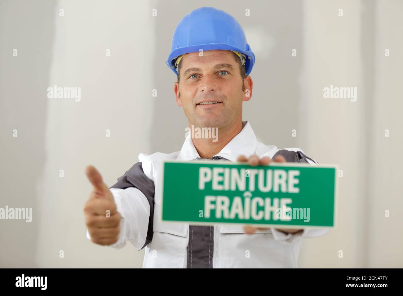 a male builder shows a wet paint sign and thumbup Stock Photo Alamy