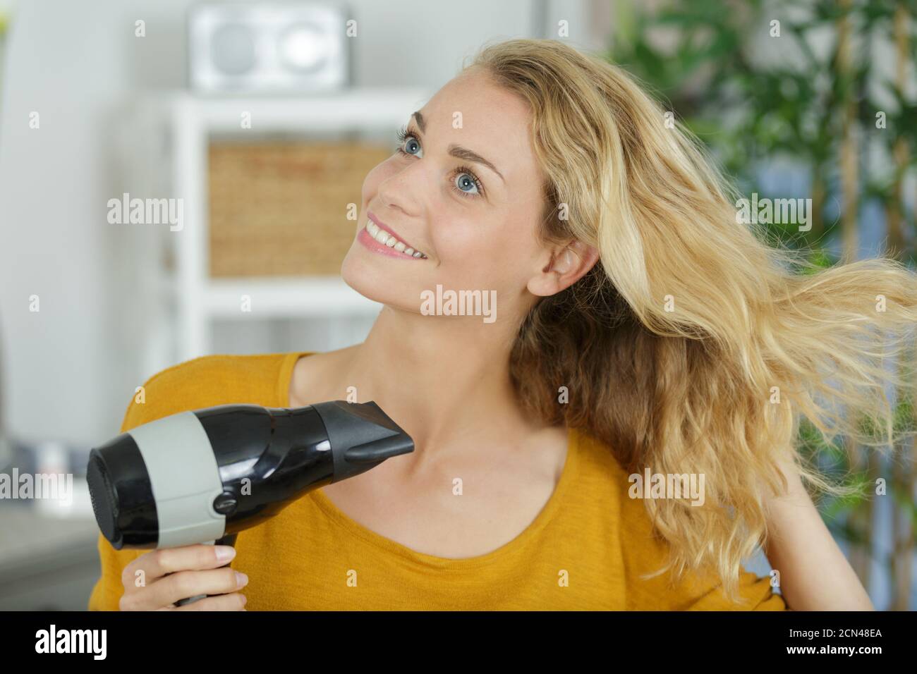 young woman drying her hair with electric blowdryer Stock Photo - Alamy
