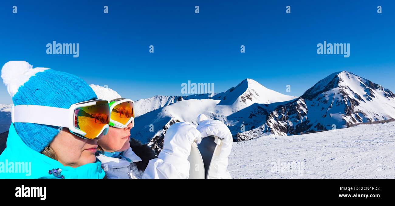 two adult female skiers stand on a mountain background Stock Photo