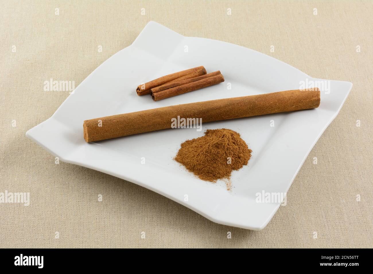 Dutch cinnamon stick snack with cinnamon stick and pile of ground cinnamon on white snack plate on light brown tablecloth Stock Photo