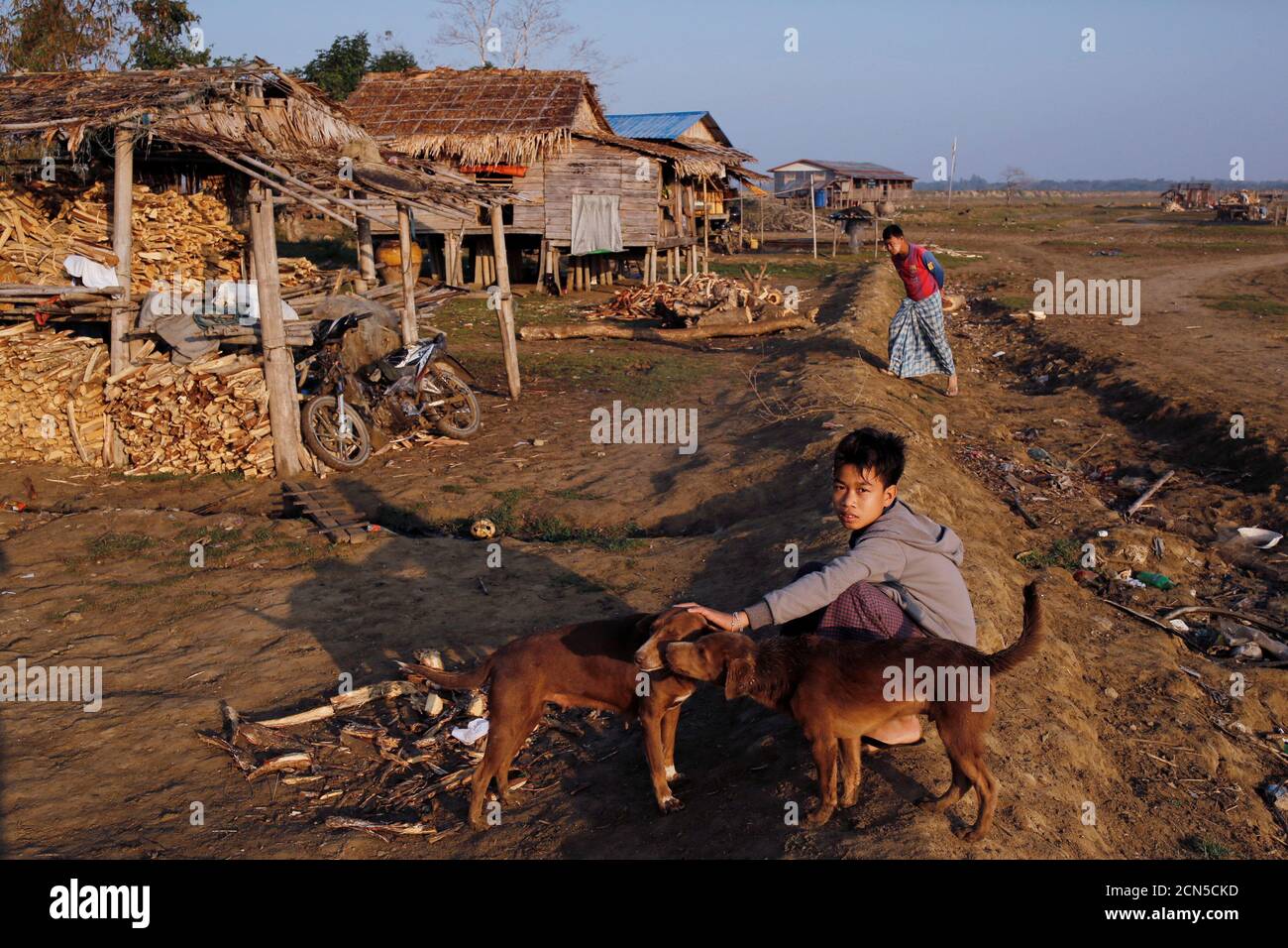A boy from Ta Dar U village pets a dog after villagers relocated their houses inland in Bago, Myanmar, February 6, 2020. Photo taken on February 6, 2020. REUTERS/Ann Wang Stock Photo