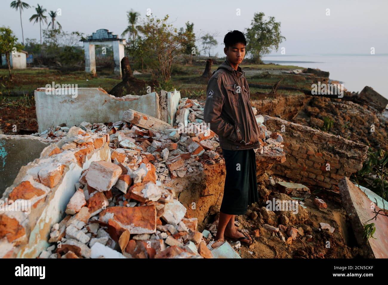 Myo Zaw, 15, stands amid the ruins of a monastery after the riverbank is was located on collapsed into the water in Ta Dar U village,Bago, Myanmar, February 6, 2020. Photo taken on February 6, 2020. REUTERS/Ann Wang Stock Photo