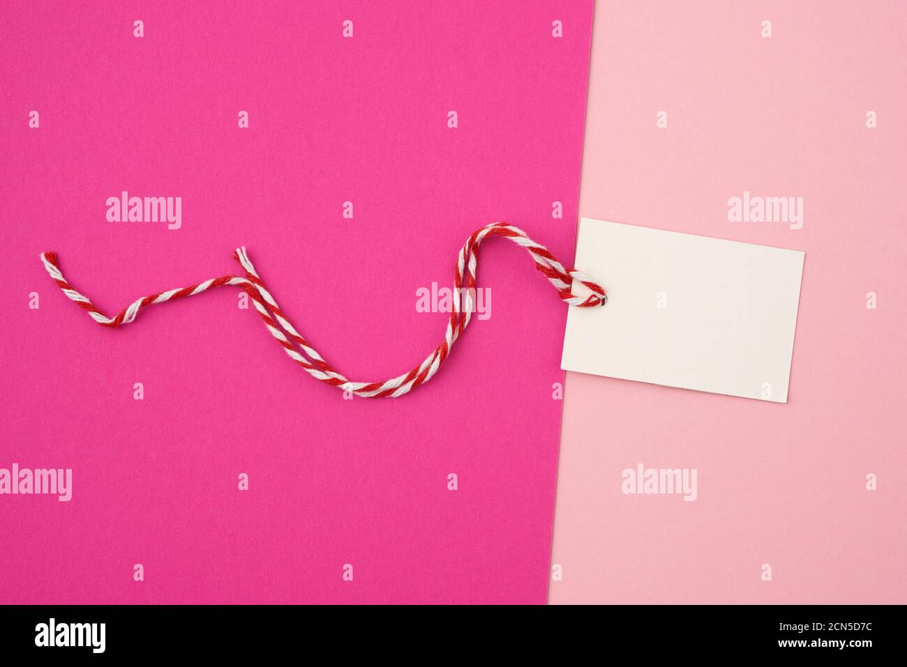white paper rectangular tag on a rope on a colored background, flat lay Stock Photo