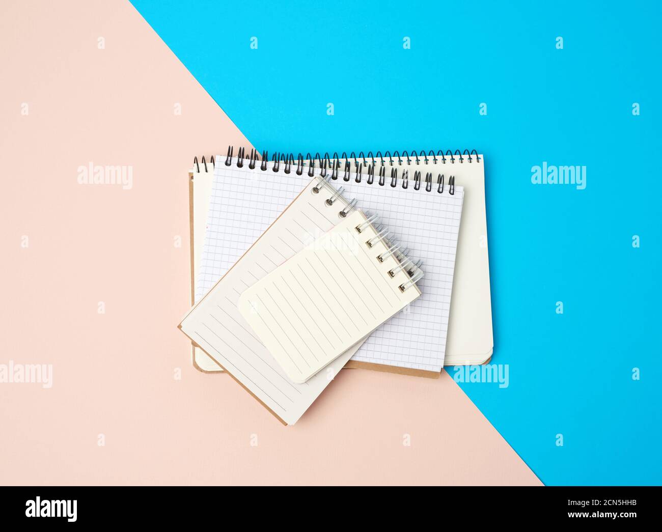 stack of spiral open notebooks with blank white sheets on a blue background Stock Photo