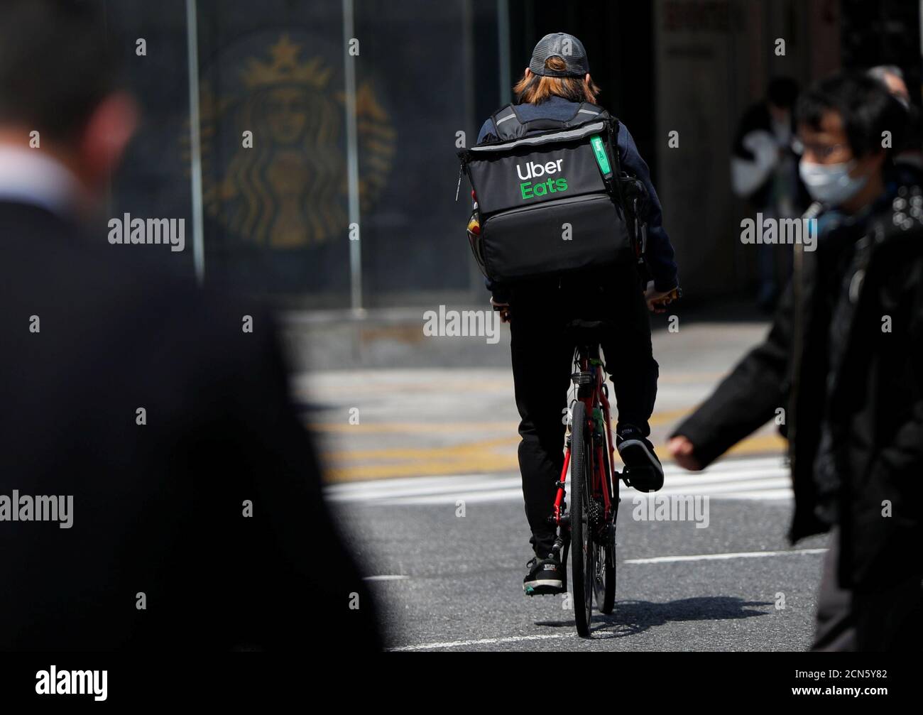 An Uber Eats delivery person rides a bicycle during an outbreak of