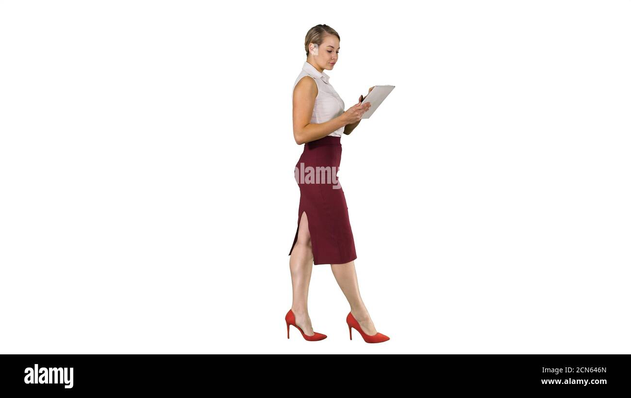 Businesswoman using electronic tab walking on white background. Stock Photo