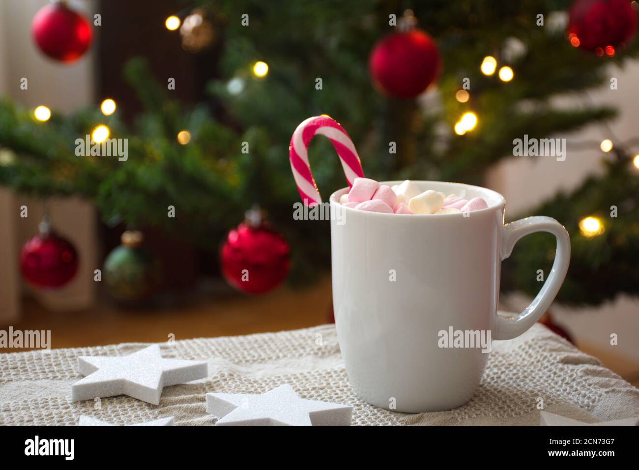 https://c8.alamy.com/comp/2CN73G7/cup-of-coffee-with-candy-cane-in-front-of-christmas-tree-2CN73G7.jpg