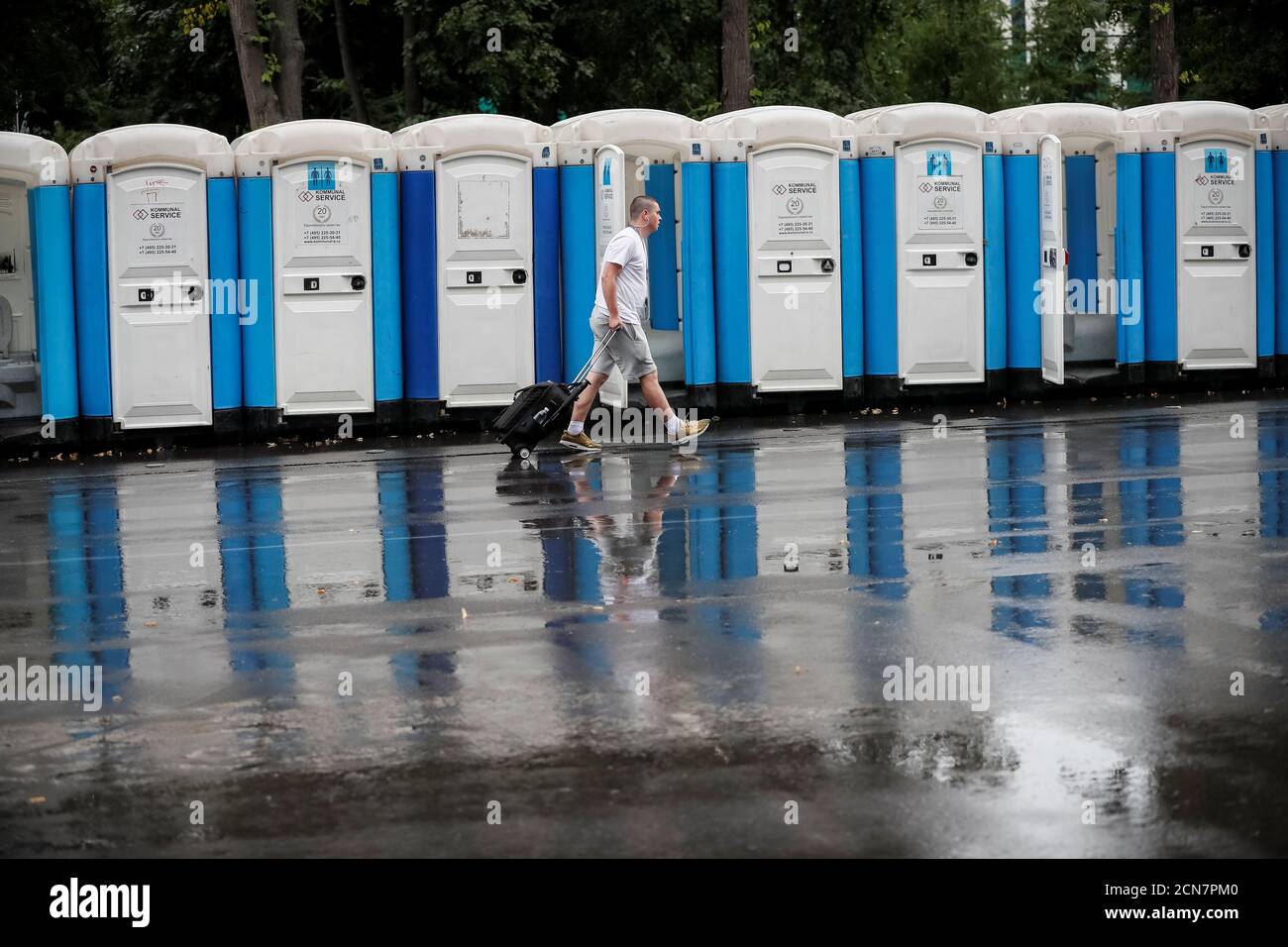 A photographer walks past mobile toilets at Luzhniki stadium in Moscow, Russia July 14, 2018. As well as shooting all the matches, Reuters photographers are producing pictures showing their own quirky view from the sidelines of the World Cup. REUTERS/Gleb Garanich Stock Photo