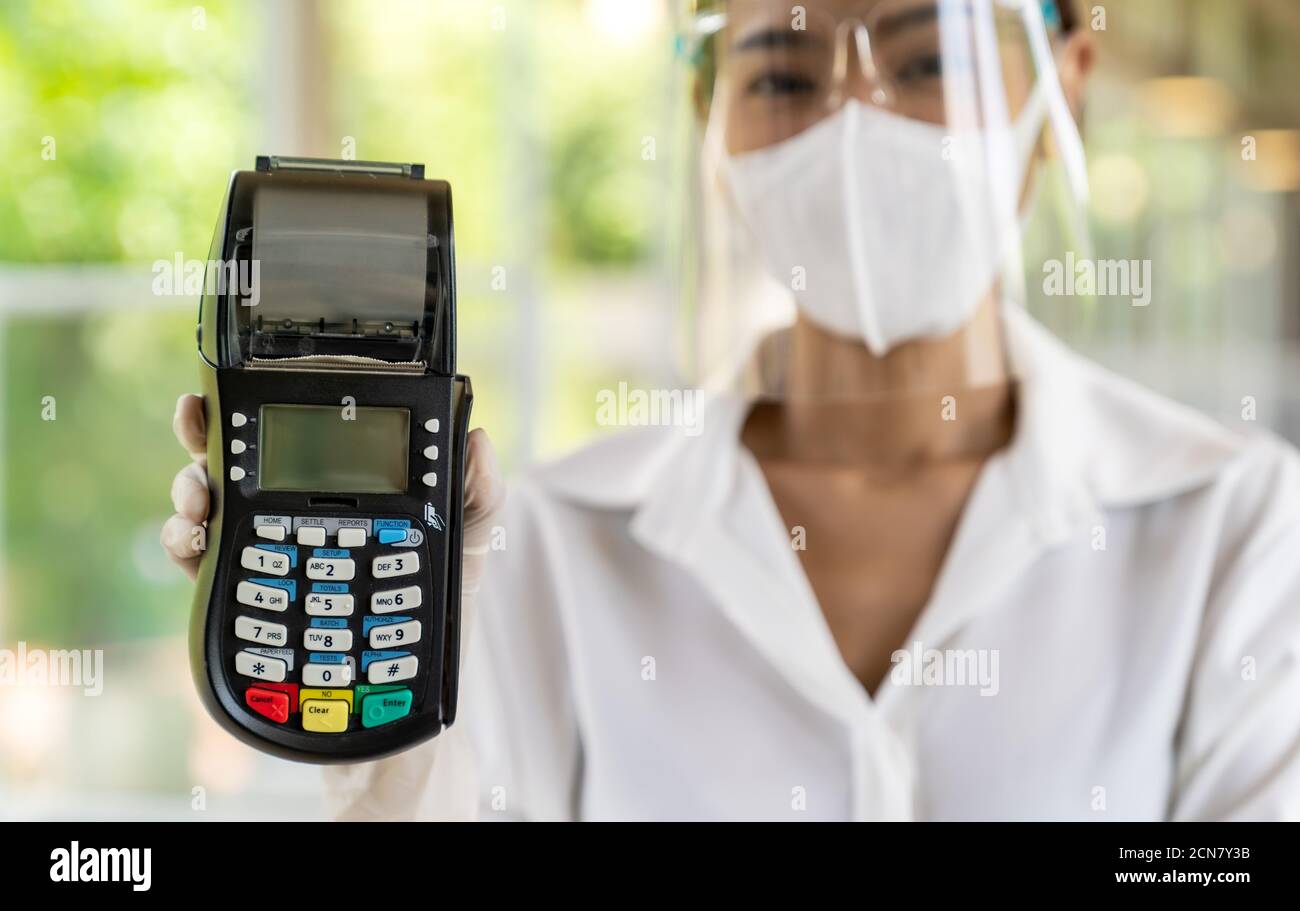 Waitress with face mask hold credit card reader. Stock Photo