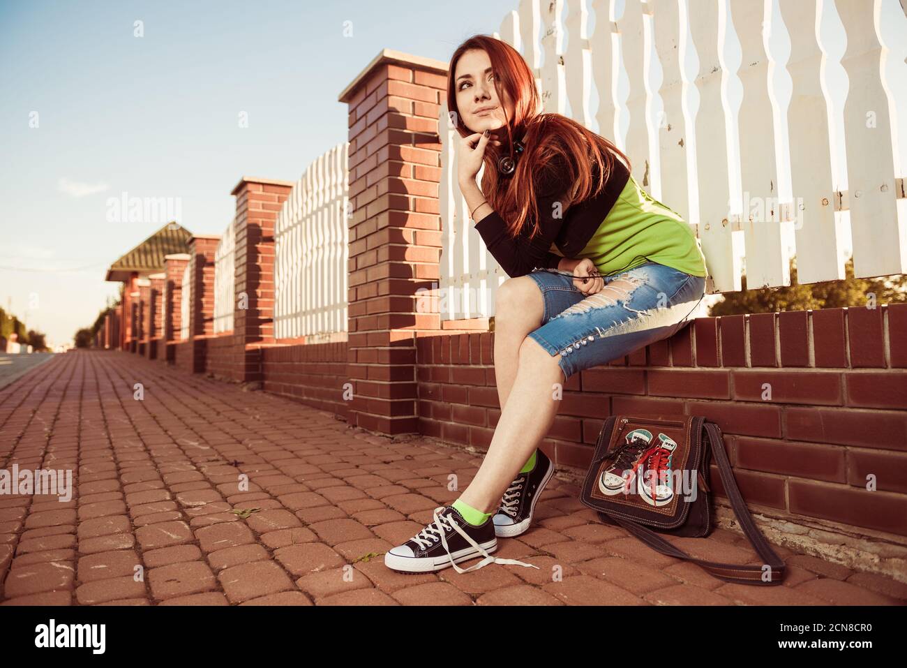 Lovely young redhead woman with earphones at uptown street sunset Stock Photo