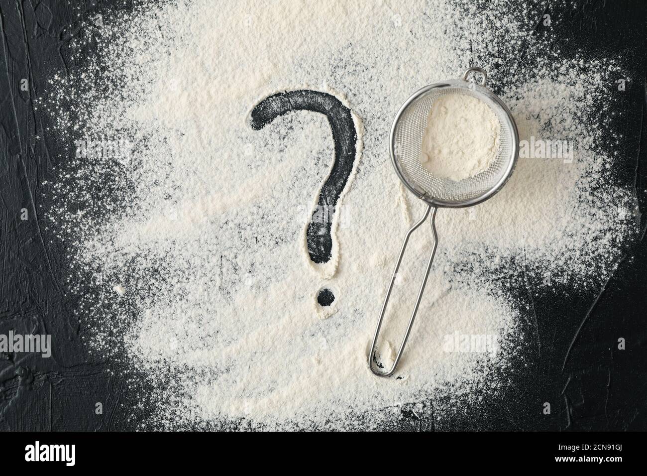 Flour, sieve and question mark on black background Stock Photo Alamy