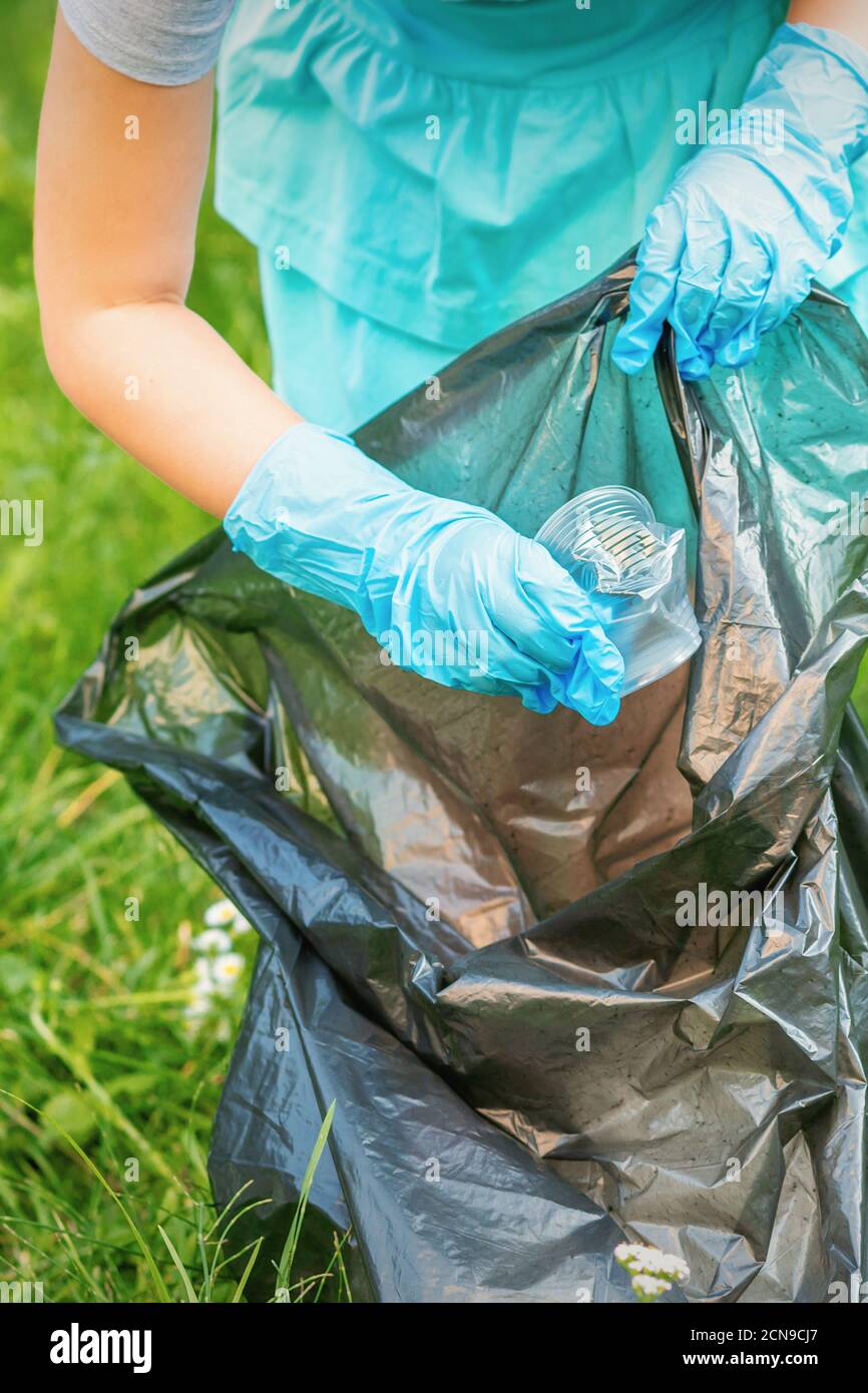 Child collects plastic trash from grass throwing garbage in garbage bag