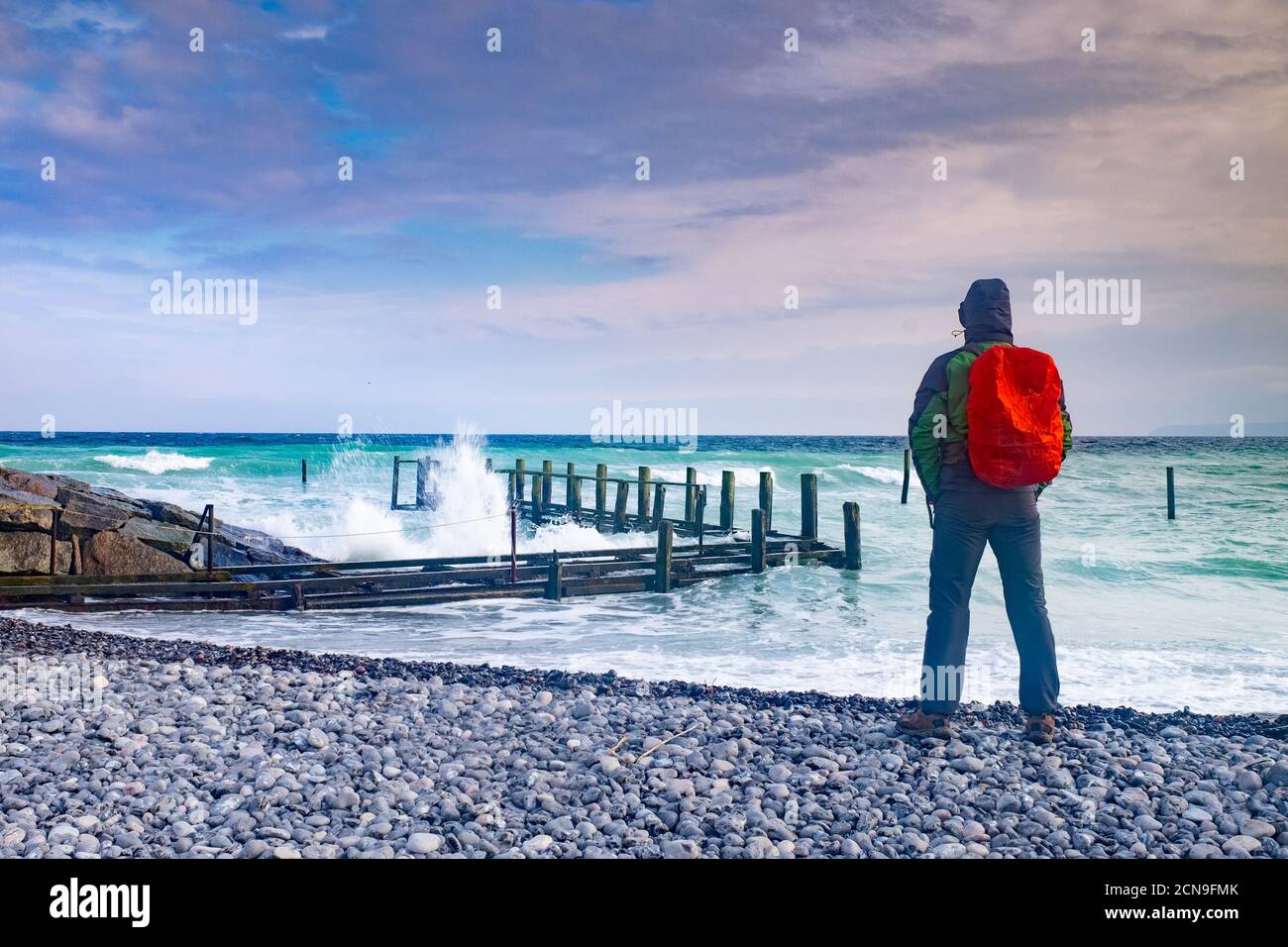 Man tourist watch how waves crash into pier Stock Photo