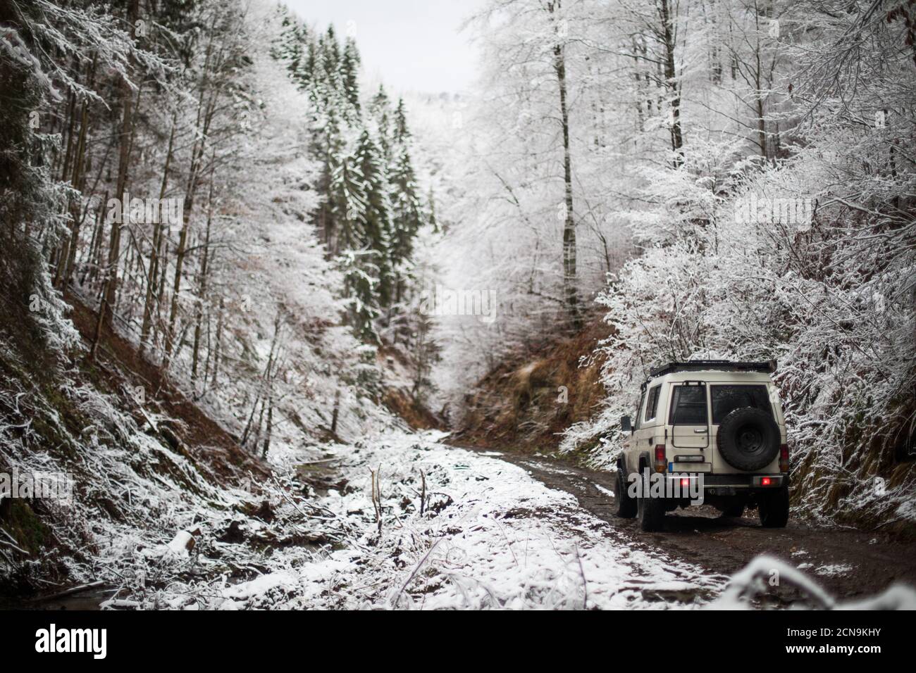 Color image of an off road car, driving on a track in a snow covered forest. Stock Photo