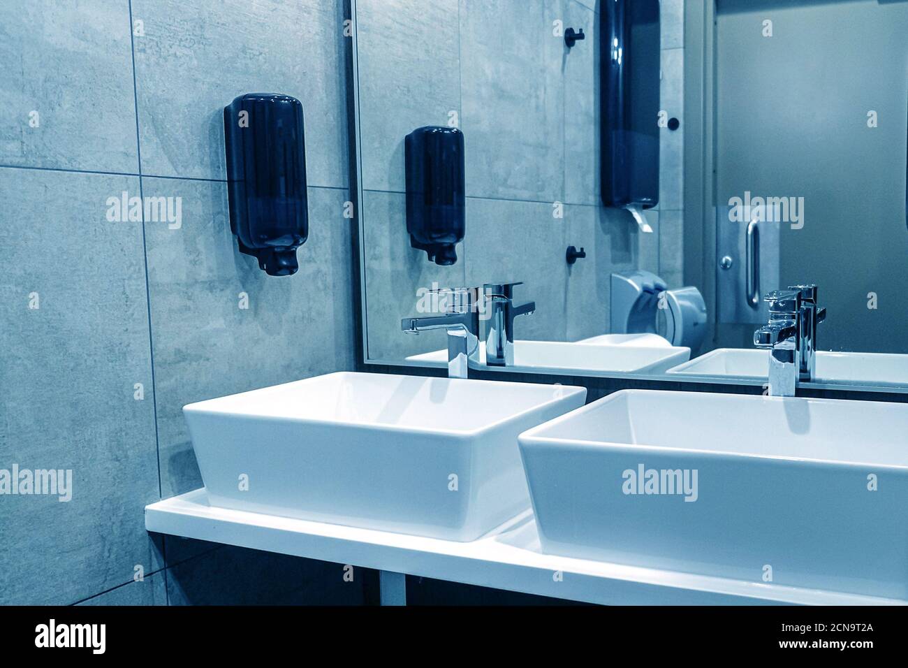 Modern sinks with a mirror in a public toilet. Bachelor's reflection in the mirrors Stock Photo