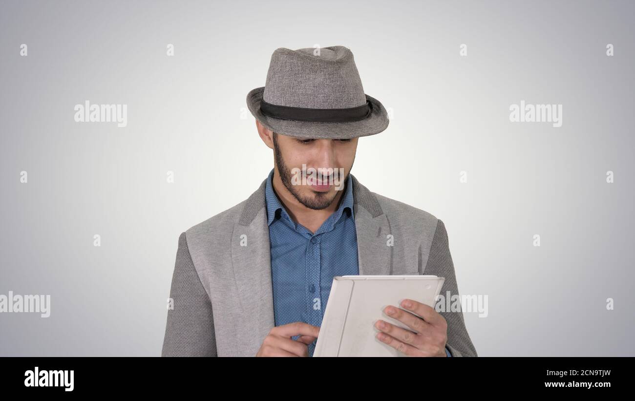 Handsome smiling arab man in a hat walking and using tablet on g Stock Photo