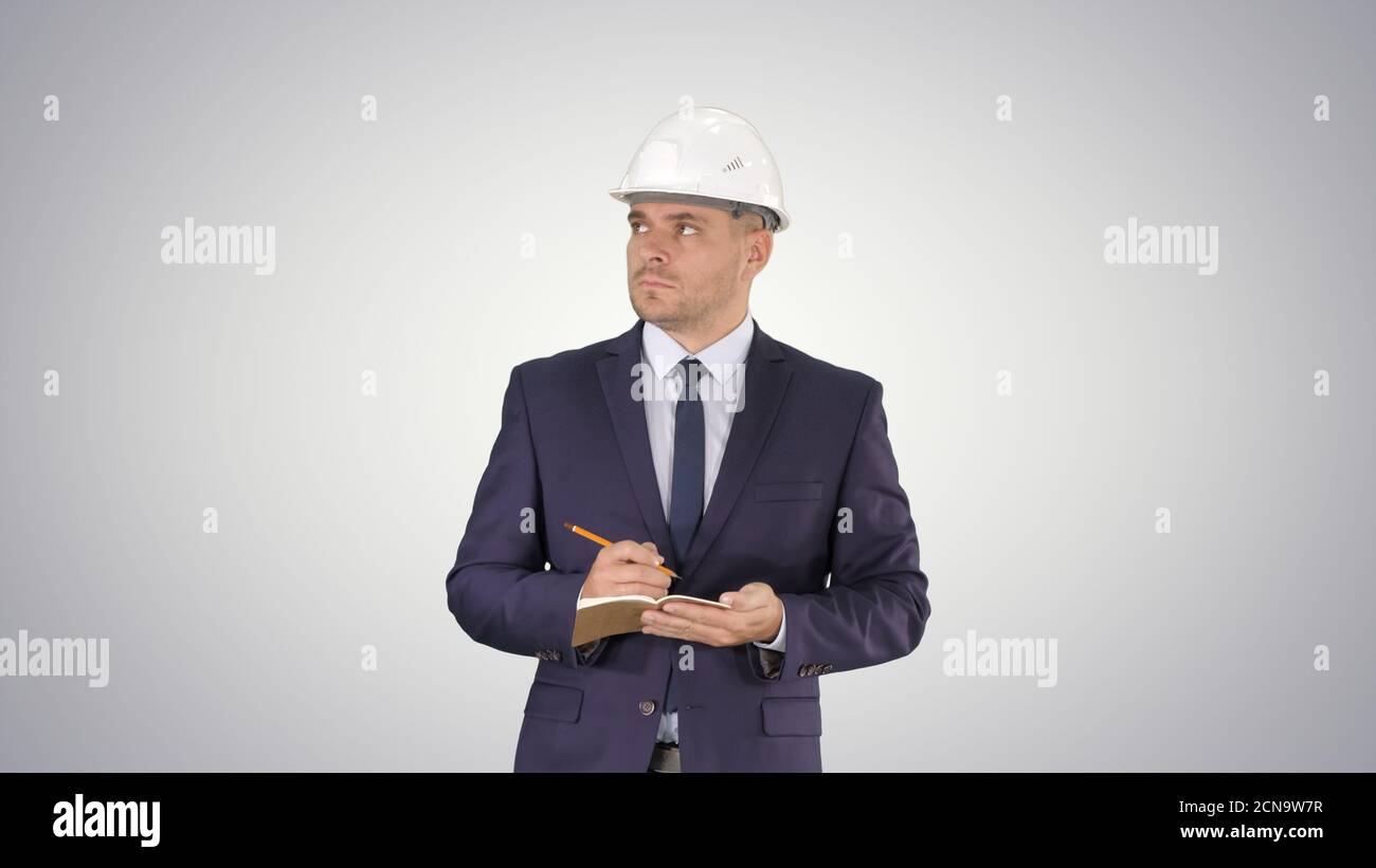 Engineer in suit and helmet walking and writing notes in notepad Stock Photo
