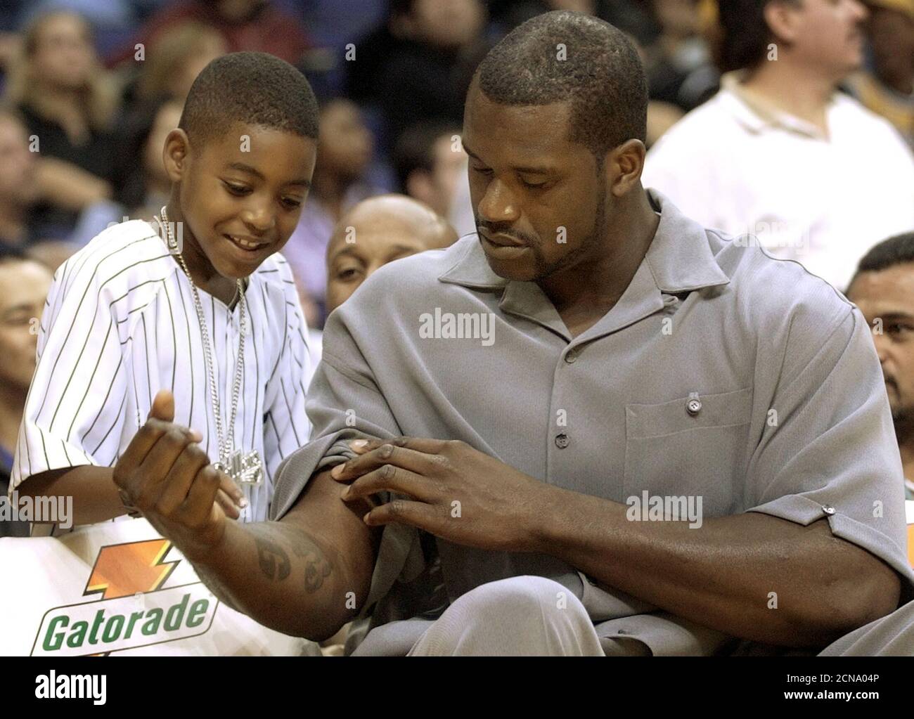 Los Angeles Lakers center Shaquille O'Neal (R) shows a young fan his  tattoos, as he sits out the game on the bench with an injured heel, during  their NBA pre-season game against