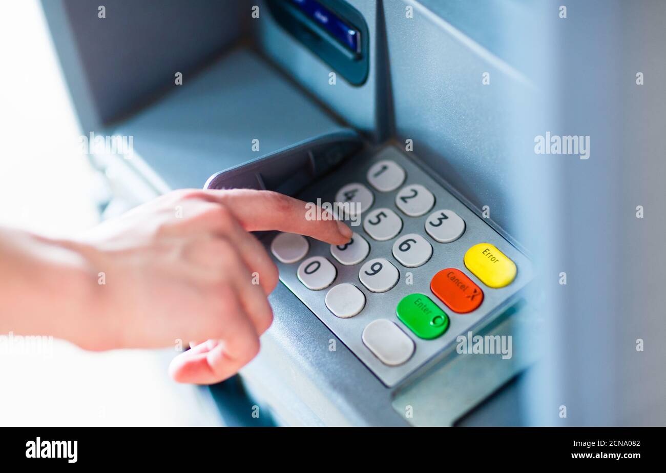 Closeup of hand entering PIN password on ATM bank machine keypad to withdraw cash money. Stock Photo
