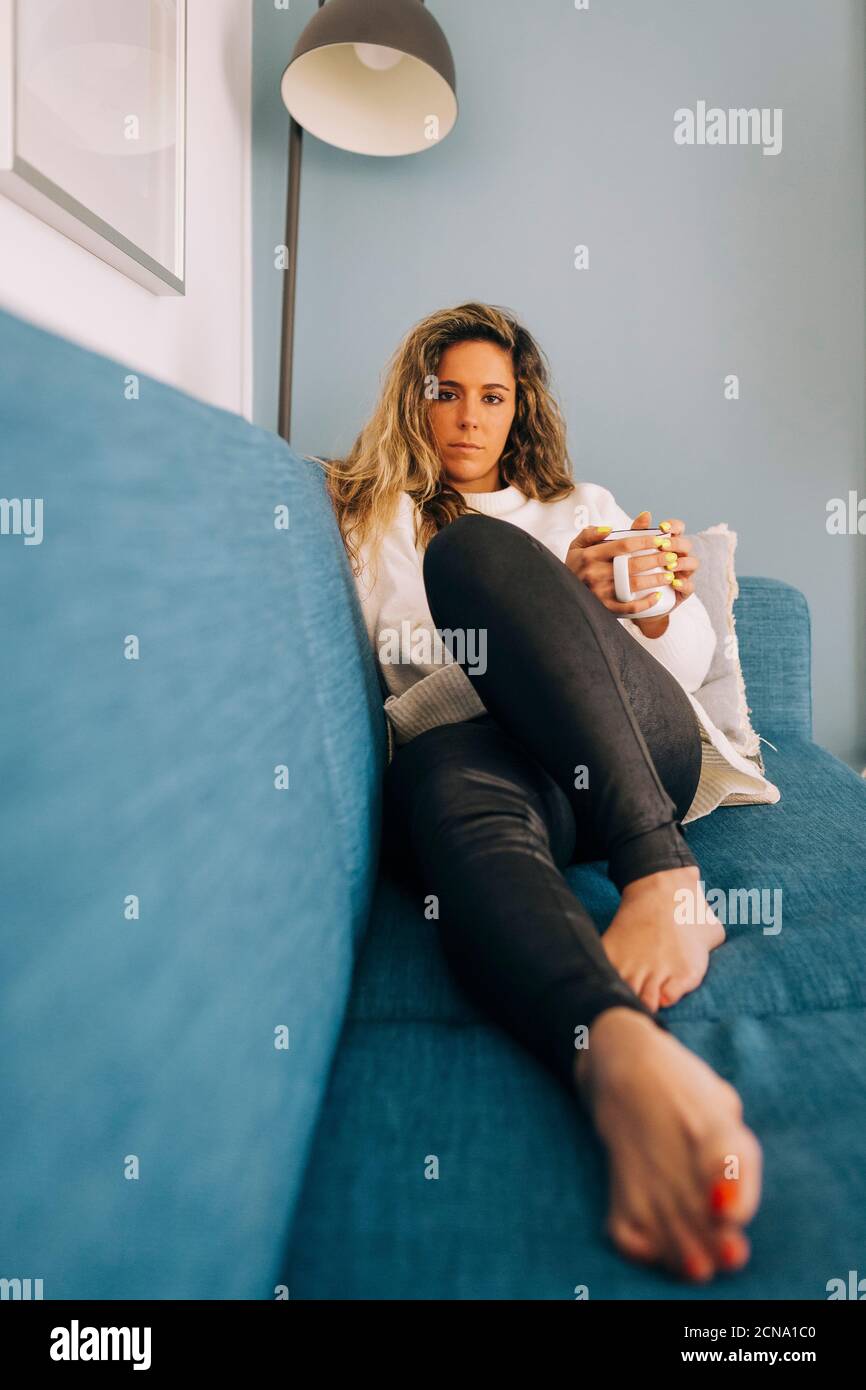 Portrait young woman relaxing on sofa with coffee Stock Photo - Alamy