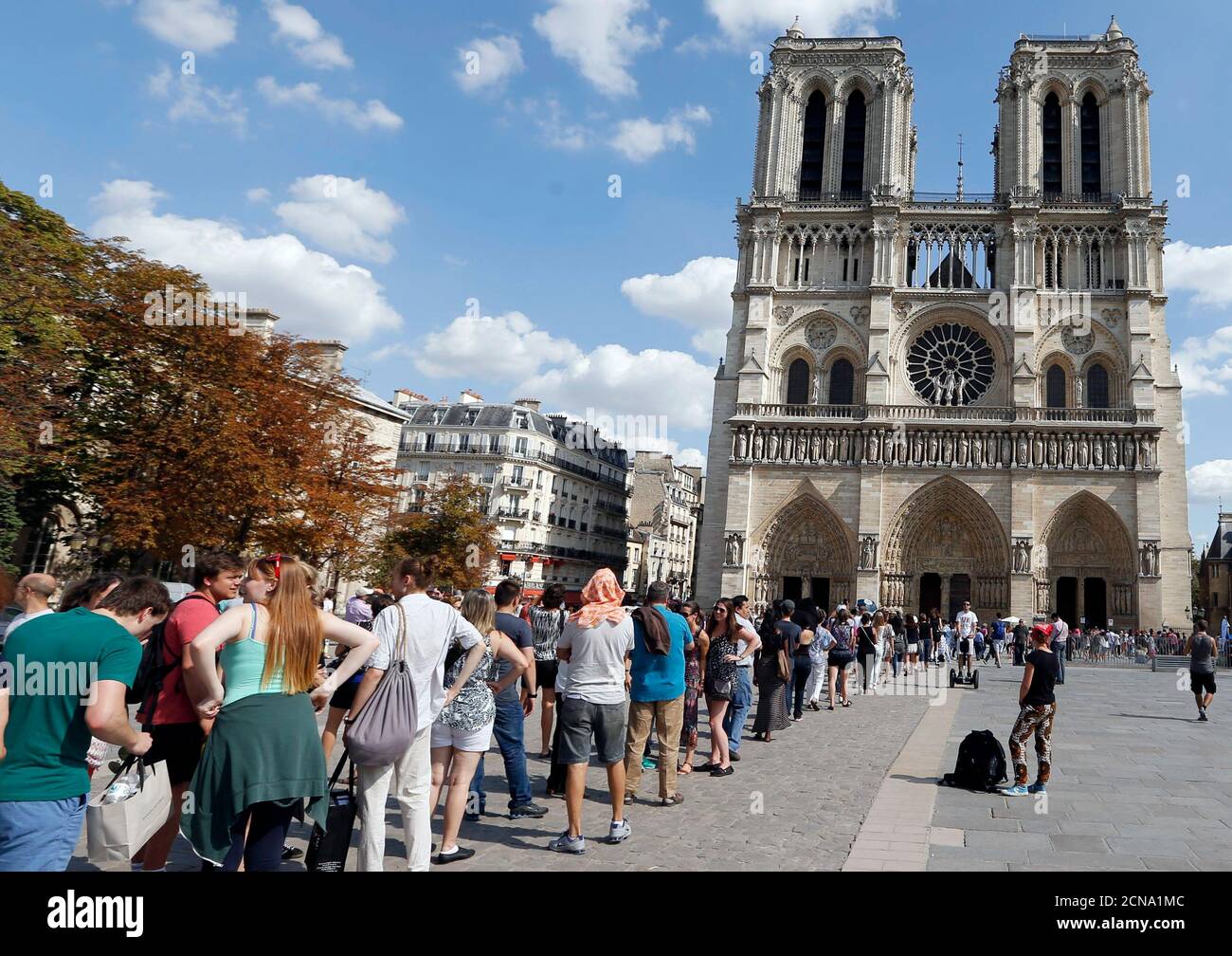 Tourists queue as they wait to visit the Notre Dame Cathedral on a warm  summer's day in Paris, France, August 21, 2015. France is on course to  welcome a record number of