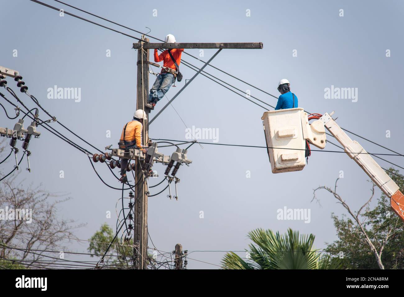 Electricians are climbing on electric poles to install and repair power line on hot days. Stock Photo